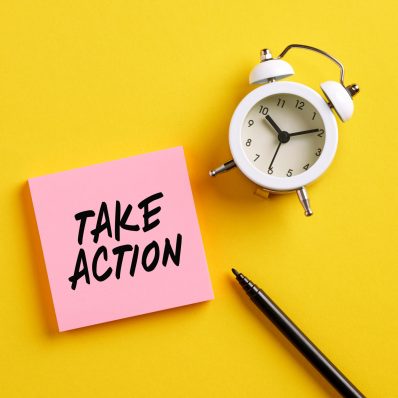 Take action message on pink note paper with alarm clock and pen. Motivational message for taking action in business or life concept.